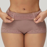 Person wearing a pair of mauve lace-trimmed underwear on a plain background